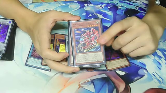 ホイール・シンクロンのカードを手に取り効果を説明する場面