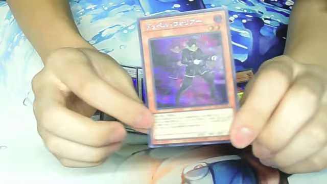 ドッペル・ウォリアーのカードをカメラへ近づけて見せるみつお