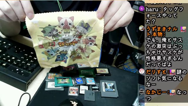 カードを広げた机で、昔のゲーム関連の小物を手に取って見せるみつお