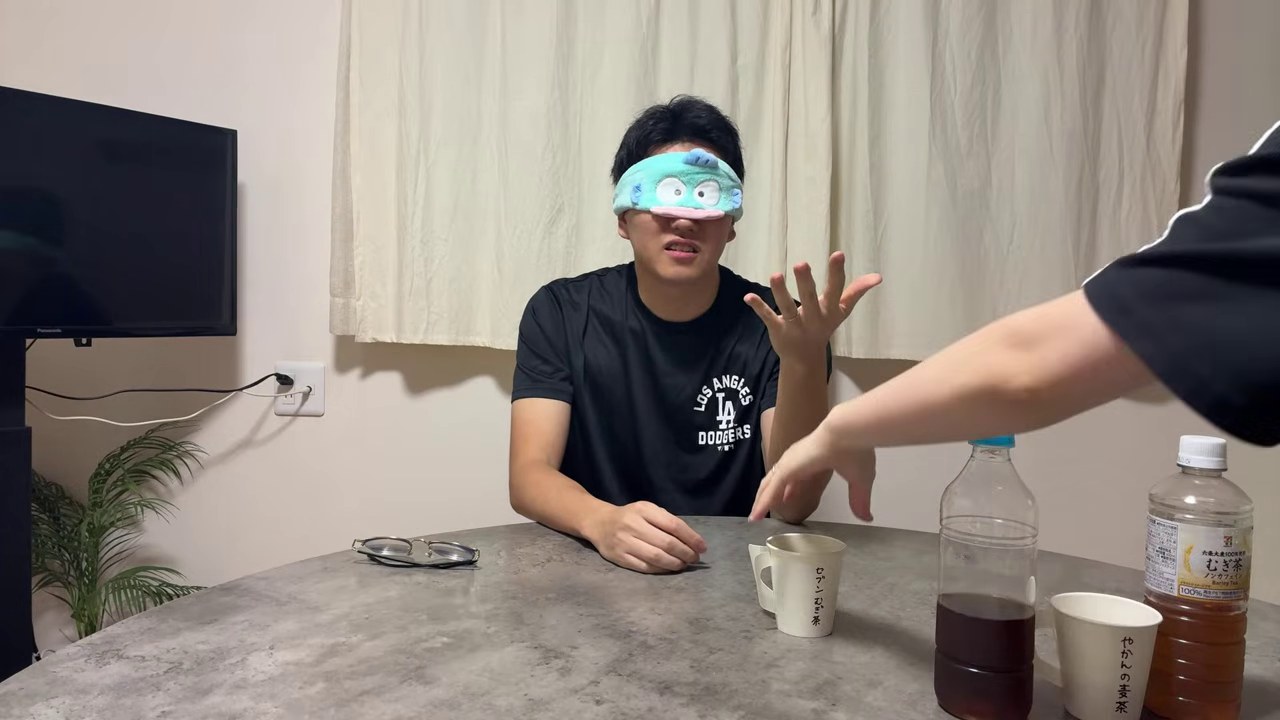目隠しをしたみつおが差し出されたカップを受け取り、飲み物の名前を考える場面