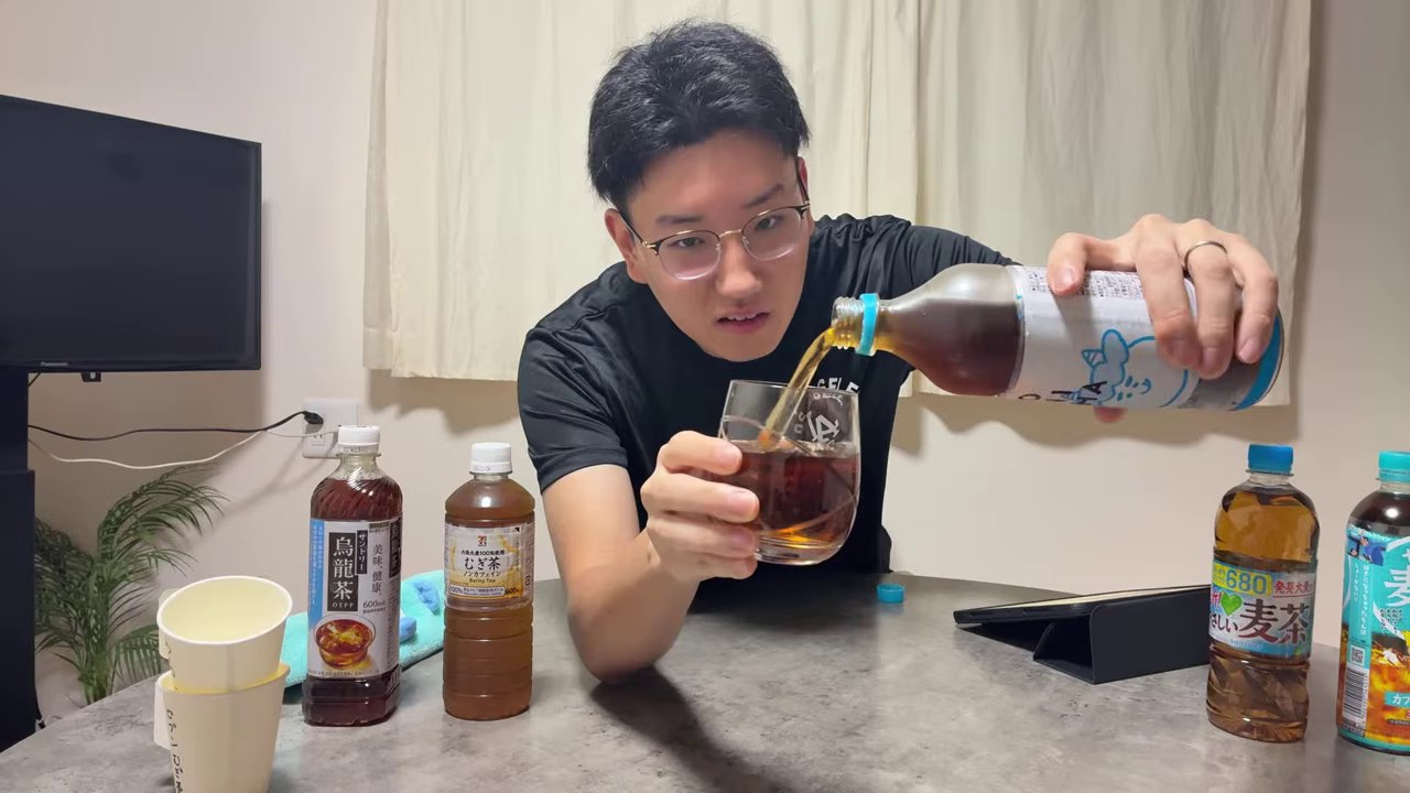 みつおがONICHAのボトルからグラスへお茶を注ぎ、卓上にほかの飲み物が並ぶ場面