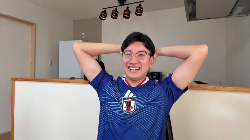 日本代表の青いユニフォームを着たみつおが、両手を頭の後ろに回して笑う視聴配信画面
