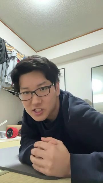 運動後のみつおがマットの上からカメラに近づき、公開チャットを見ながら話している場面