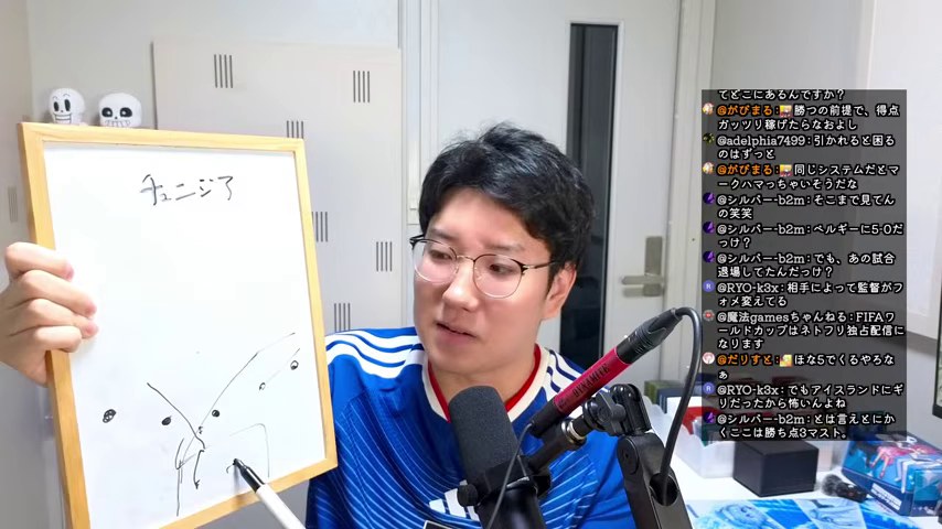 『チュニジア』と守備の位置を描いたボードを示しながら話すみつお