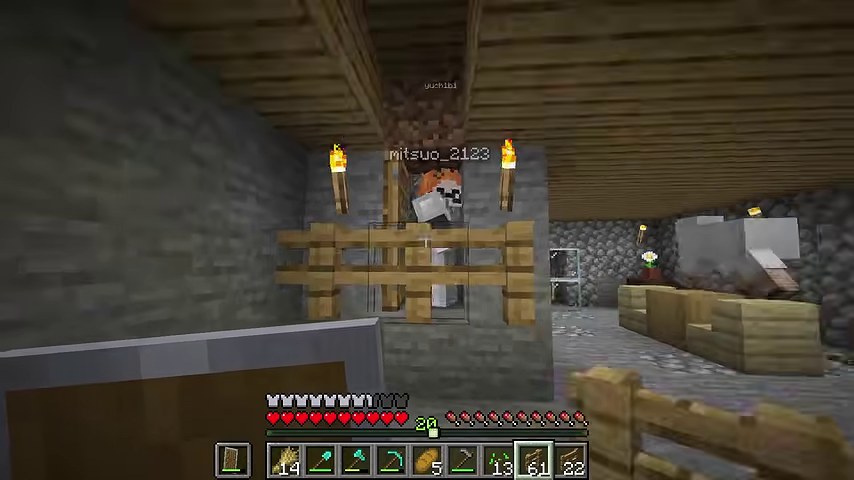 マインクラフトの石の部屋で、オレンジ髪のみつおが木の柵の向こうに立つ場面