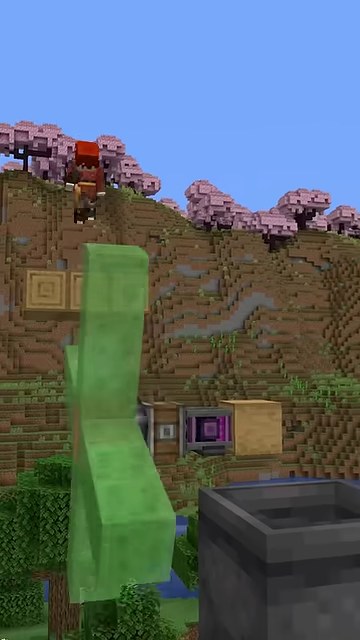 赤い服の山田が高い足場からスライムの柱を狙い、奥に桜の木が見えるマイクラの縦画面